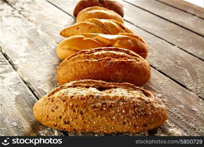 Breads varied in a row on rustic wood table with wheat flour