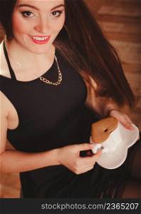 Break and relax time. Elegant beauty woman in black dress holding and drinking hot fresh coffee in white heart shaped cup mug. Girl with cake cupcake dessert.. Woman with cup of coffee and cake