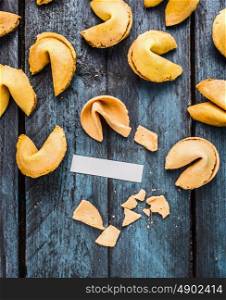 break fortune cookie with blank paper tag on blue wooden background, top view, coipy space