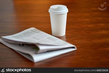 break, mass media and news concept - coffee drink in paper cup and newspaper on table