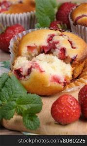 Break muffin with strawberries on a table among the berries and mint