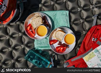 Breakfast at camping outdoors. Plates with sandwiches on outdoor mat. Concept of camp life