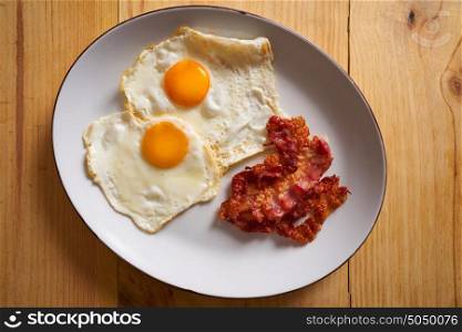 Breakfast bacon and eggs over easy on wood table