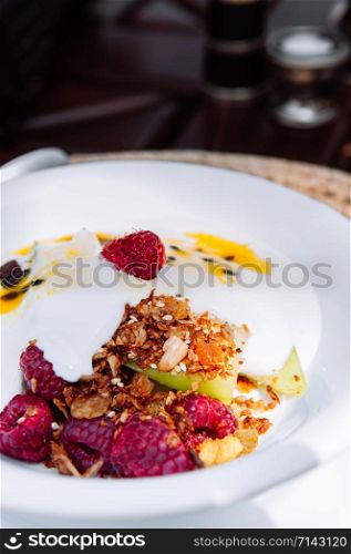 Breakfast berry yogurt mousli with raspberry apple almond and fresh sour sweet passion fruit sauce, light healthy breakfast