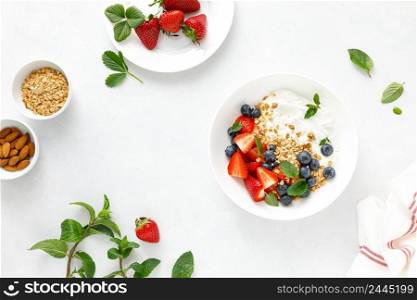 Breakfast bowl with granola, plain yogurt, strawberry and blueberry, top view