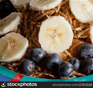 Breakfast cereal with bananas blueberries and bran flakes in bowl