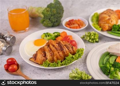 Breakfast consisting of bread, fried eggs, broccoli, carrots, tomatoes and lettuce on a white plate