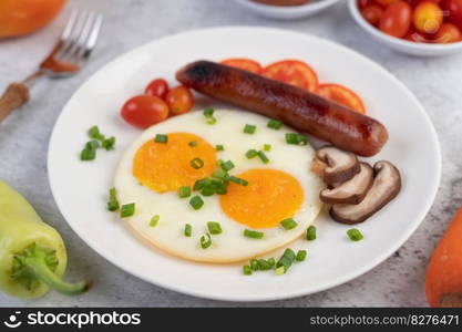 Breakfast consisting of bread, fried eggs, tomatoes, Chinese sausage and mushrooms