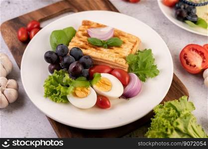 Breakfast consists of bread, boiled eggs, black grape salad dressing, tomatoes, and sliced   onions.