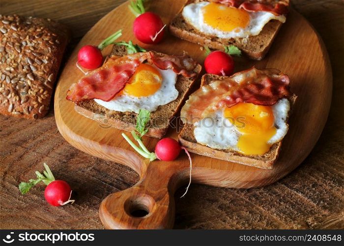 Breakfast , crispy bacon, fried eggs and bread. Sandwiches on cutting board. Rustic table . Top view .. Breakfast , crispy bacon, fried eggs and bread. Sandwiches on cutting board. Rustic table . Top view