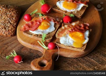 Breakfast , crispy bacon, fried eggs and bread. Sandwiches on cutting board. Rustic table . Top view .. Breakfast , crispy bacon, fried eggs and bread. Sandwiches on cutting board. Rustic table . Top view