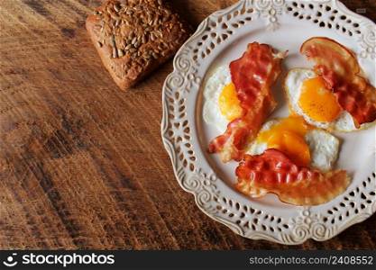 Breakfast , crispy bacon, fried eggs and bread. Sandwiches on white plate. Rustic table . Top view .. Breakfast , crispy bacon, fried eggs and bread. Sandwiches on white plate. Rustic table . Top view