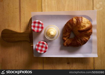 Breakfast croissant with butter and jam on wood board