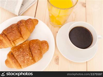 Breakfast - Croissants, Coffee, Orange Juice and Newspapers on Wooden Table