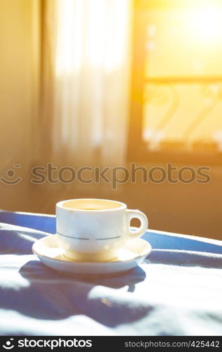 Breakfast - cup of coffee and a window with the sun in the background