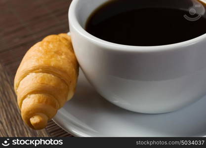 Breakfast. Cup of coffee and croissant on saucer