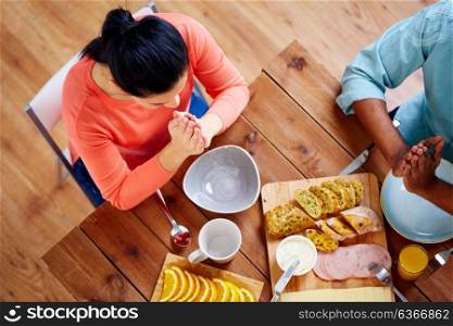 breakfast, family and religious concept - people with food sitting at table and praying before meal. woman sitting at table and praying before meal