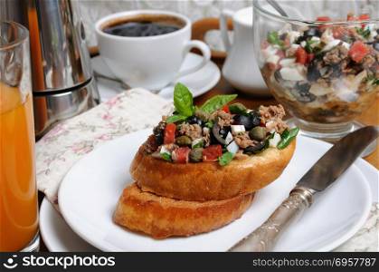 Breakfast from fried toast with chopped tuna with egg, cubes of tomatoes and olive slices, capers with a cup of coffee, a coffee pot on a tray. Breakfast with croutons and coffee
