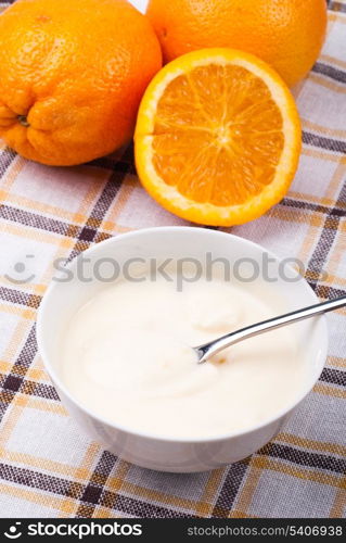 Breakfast from yoghurt with cornflakes and orange over tablecloth