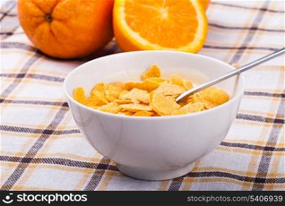 Breakfast from yoghurt with cornflakes and orange over tablecloth