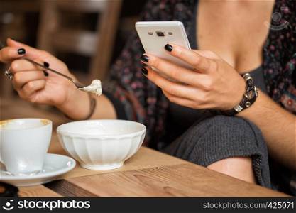breakfast - girl sitting with smartphone and a cup of coffee and dessert