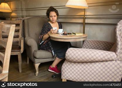 breakfast - girl sitting with smartphone and a cup of coffee at the cafe