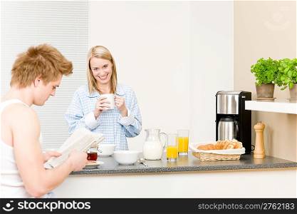 Breakfast happy couple drink coffee and read newspaper in kitchen