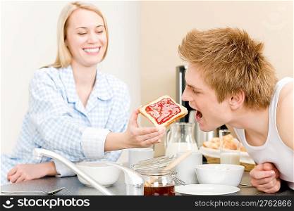 Breakfast happy couple man feed toast to woman in kitchen