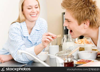 Breakfast happy couple woman feed cereal to man in kitchen