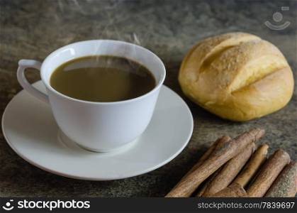 breakfast. hot coffee with bread and cinnamon sticks on wooden background