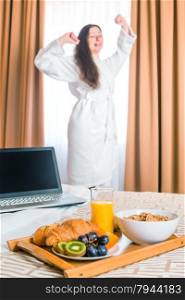 Breakfast in bed and stretches himself a woman in a bathrobe