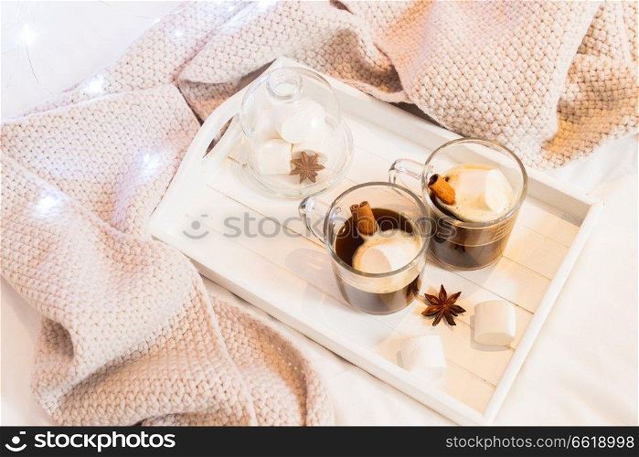 Breakfast in bed for two - tray with cup of coffee and sweet marshmallows, cozy hygge home style with scarf. Breakfast in bed
