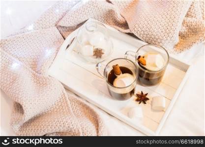 Breakfast in bed for two - tray with cup of coffee and sweet marshmallows, cozy hygge home style with scarf. Breakfast in bed