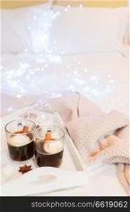 Breakfast in bed for two - tray with cup of coffee and sweet marshmallows, cozy winter hygge home style with lights. Breakfast in bed