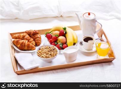 breakfast in bed. Tray with coffee, croissants, cereals and fruits
