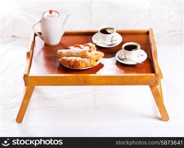 Breakfast in bed. Tray with cups of coffee and pastry