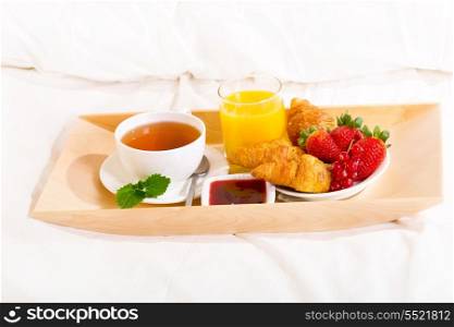 breakfast in bed with tea, croissants and juice