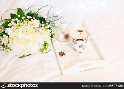 Breakfast in bed - wooden tray with warm drink and flowers, cozy hygge home style. Breakfast in bed