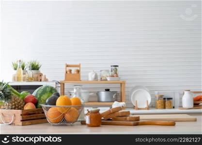 Breakfast ingredients are on kitchen table at home, including sliced whole wheat bread, jam, oranges, avocados, watermelon, red and green apples, pineapples and vegetables for fresh juices and salads