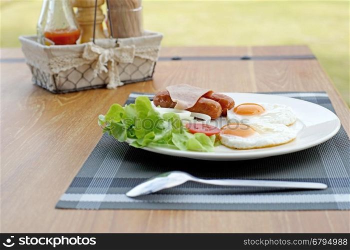 breakfast meal with ham sausage egg and salad on wooden background