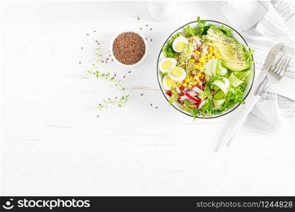 Breakfast oatmeal porridge with fresh vegetable salad of cucumber, radish, lettuce, corn, avocado, chia seeds and boiled eggs. Healthy balanced food. Top view. Flat lay