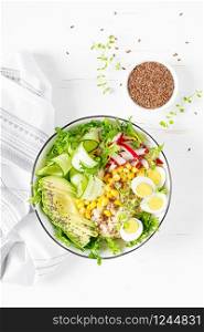 Breakfast oatmeal porridge with fresh vegetable salad of cucumber, radish, lettuce, corn, avocado, chia seeds and boiled eggs. Healthy balanced food. Top view. Flat lay