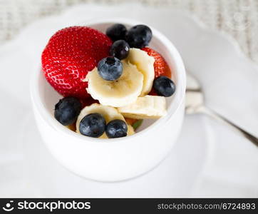 Breakfast of blueberries, strawberries with banana in glass bowl