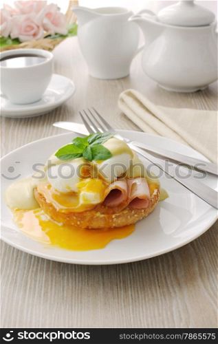 Breakfast of boiled eggs (poached) with ham on a bun with mustard sauce