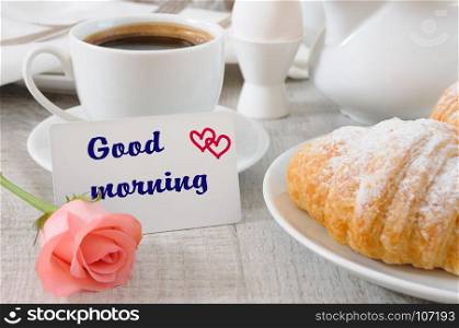 Breakfast of croissants chocolate filling cup of fresh morning coffee and a card with a wish Good morning.