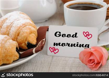 Breakfast of croissants chocolate filling cup of fresh morning coffee and a card with a wish Good morning.