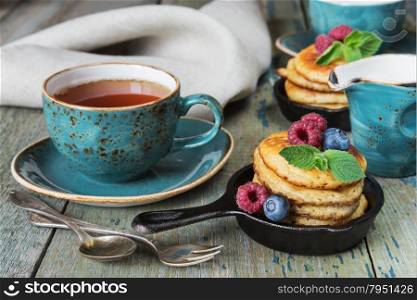 Breakfast of pancakes, fresh berries and black tea in rustic style