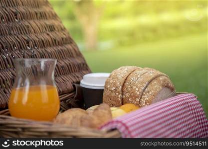 breakfast pastry tasty with bread and orange juice on wooden picnic basket in the fresh green park. Soft sweet healthy organic drink with coffee cup and croissant pastry bakery. Picnic Basket park