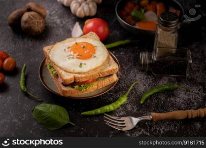 Breakfast sandwich made with bread, fried egg, ham, and lettuce.