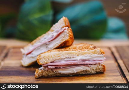 Breakfast sandwich with bacon, cheese and tomato sauce on wooden board